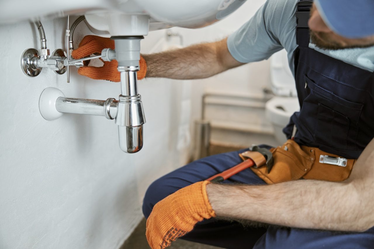 male plumber hands repairing pipe under sink.jpg